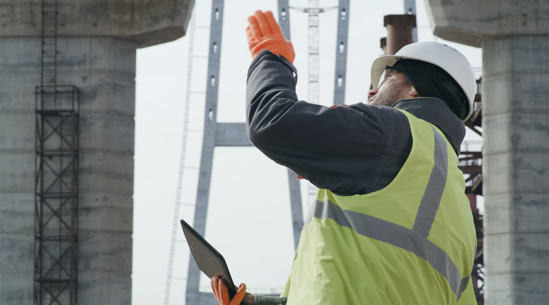 construction worker in high-visibility uniform and tablet discussing bridge construction