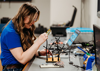 Technician working on some wiring using a magnifying glass