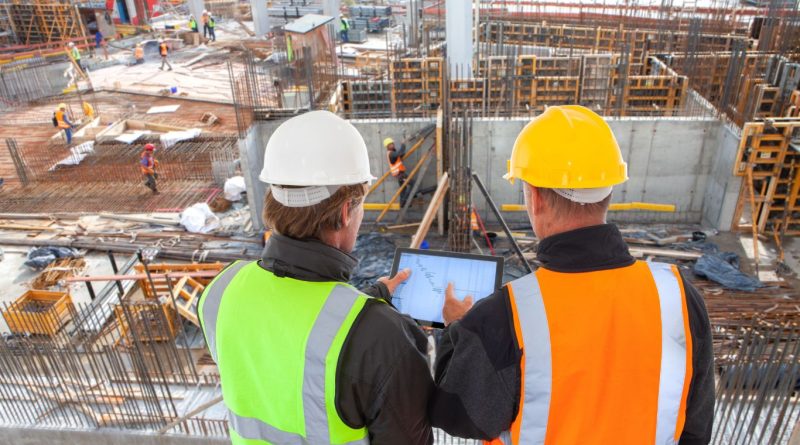 Construction managers using digital tools to track cost-efficient building methods on-site, showcasing modern construction technologies and project optimization.