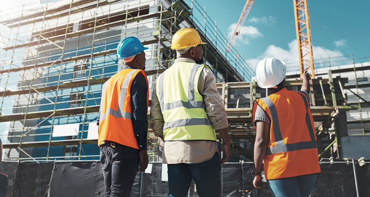 Three builders looking at a building in scaffolding