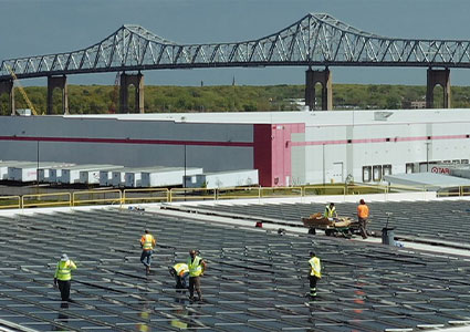 Workers installing solar panels on the rooftops of warehouses