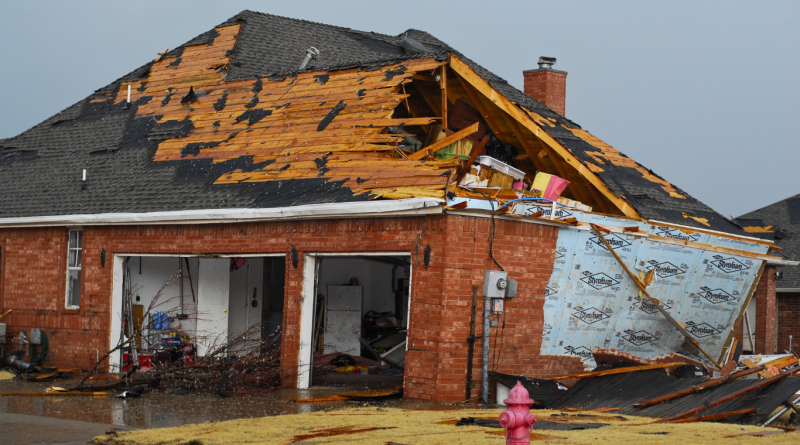 Storm-damaged brick house with a collapsed roof, highlighting construction challenges from extreme weather.