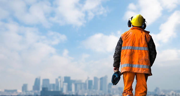 construction worker wearing a hard hat, ear defenders, and a high-visibility vest