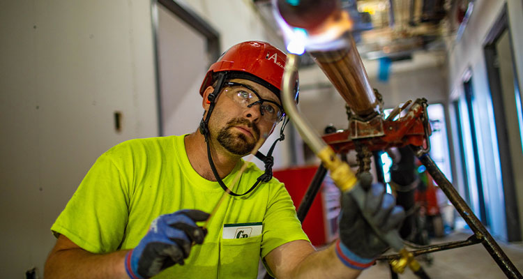 Ahern’s core purpose is to create and maintain systems that save lives, improve the environment, and ensure personal comfort and well-being a pipefitter or plumber, working on a piping system