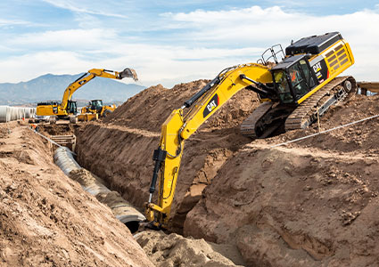 two Caterpillar (Cat) excavators working on a pipeline construction site
