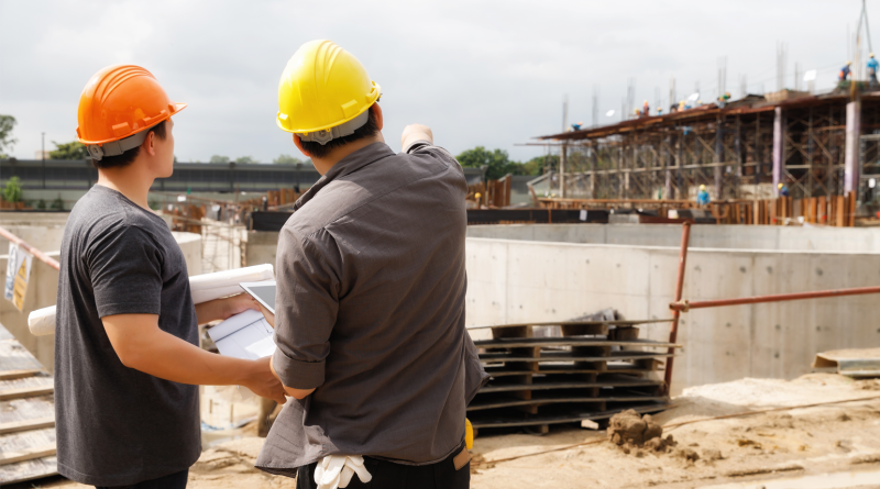 Team of construction workers discussing project details with blueprint in construction site