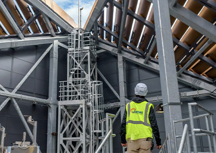 a worker inspecting a industrial scaffold system installed within a large structural steel building
