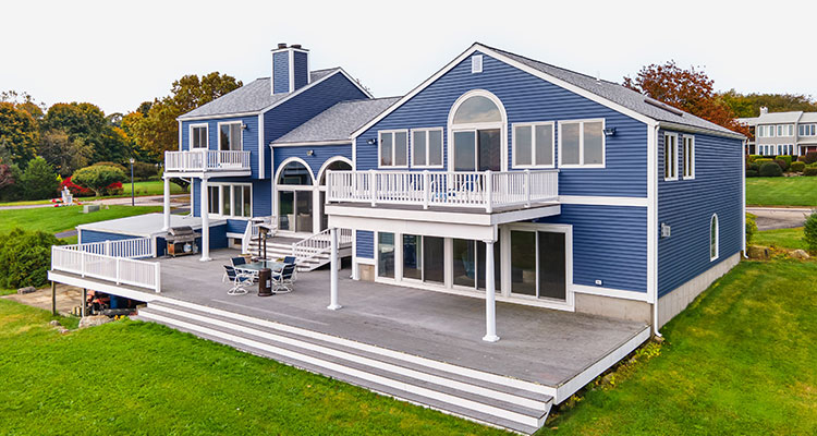 a large, blue, two-story house with extensive decking and water view
