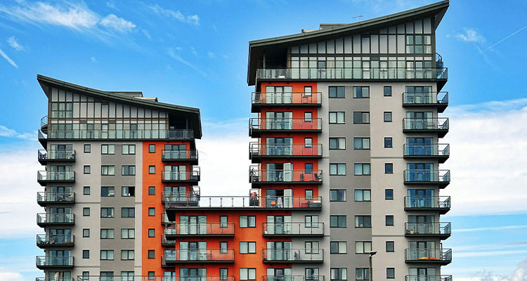 a modern apartment building complex featuring two high-rise towers connected by a lower bridging structure