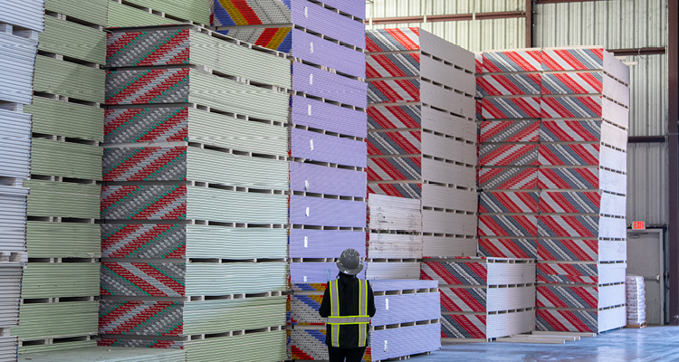 a warehouse storage facility stocked with large stacks of drywall or plasterboard panels