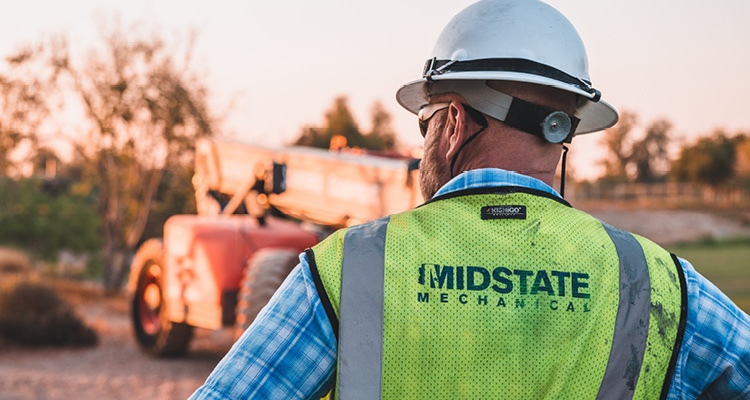 a worker wearing a high-visibility vest branded with "Midstate Mechanical"