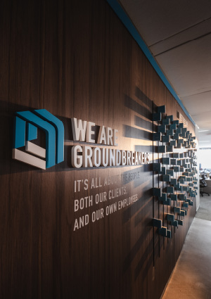 A wooden wall branded with the NewGround logo and slogan "We are groundbreaking"