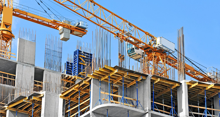 a construction site featuring a prominent yellow tower crane and concrete formwork for a high-rise building