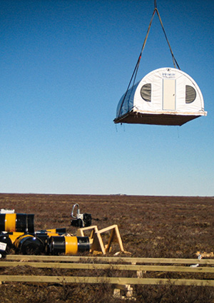 a Discovery Mining Services remote camp unit being lifted by a crane to be installed in a tundra environment
