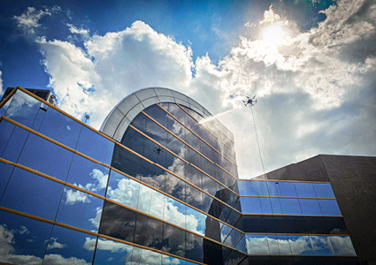 an ABZ Innovation C10 cleaning drone utilizing a high-pressure spraying system to clean a building facade