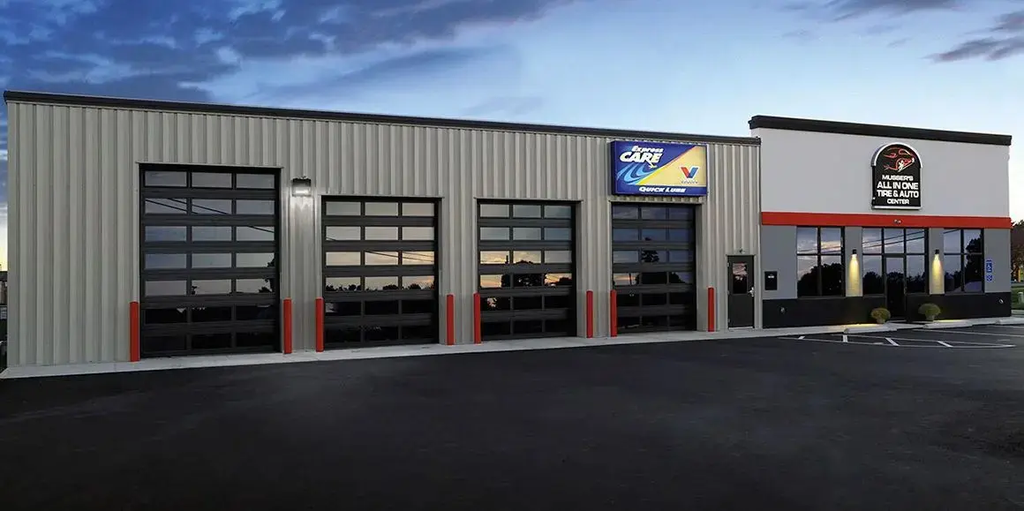 Commercial glass panel overhead doors installed at an automotive service center, combining visibility with thermal efficiency for climate-controlled facilities.