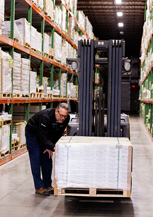 a warehouse aisle with a forklift and a person leaning over a pallet