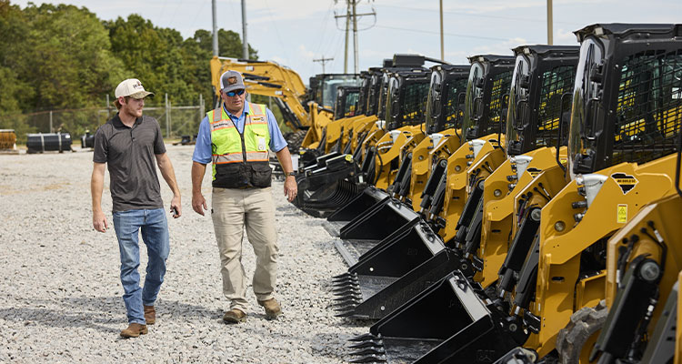 a line of Caterpillar (Cat) compact track loaders and heavy equipment at a Cat dealership or rental yard