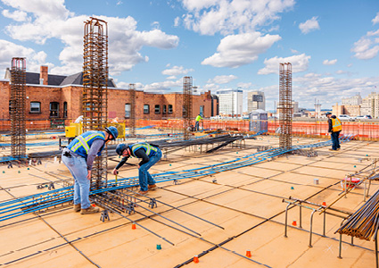 construction workers tying and placing reinforcement steel on an elevated concrete deck