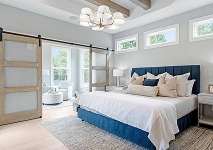 a modern bedroom featuring a large bed with a navy blue upholstered headboard and matching bed frame