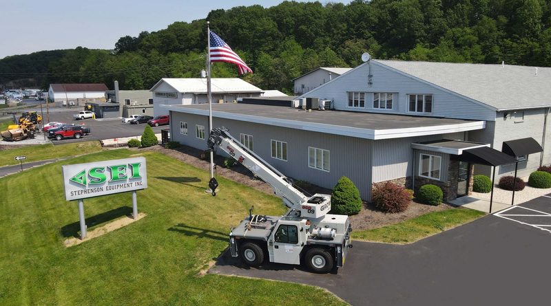 Aerial view of Stephenson Equipment Inc. (SEI) headquarters, featuring a Grove mobile crane parked outside the facility, an American flag and the company sign.