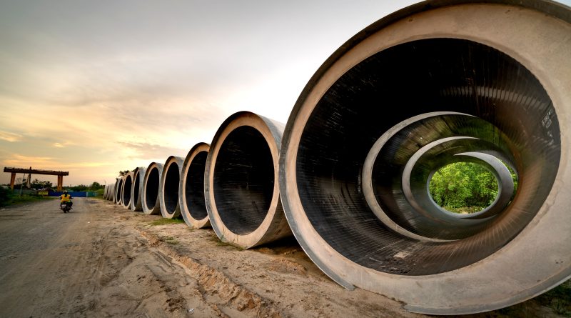 Large concrete sewer pipes lined up at a construction site for underground infrastructure installation.
